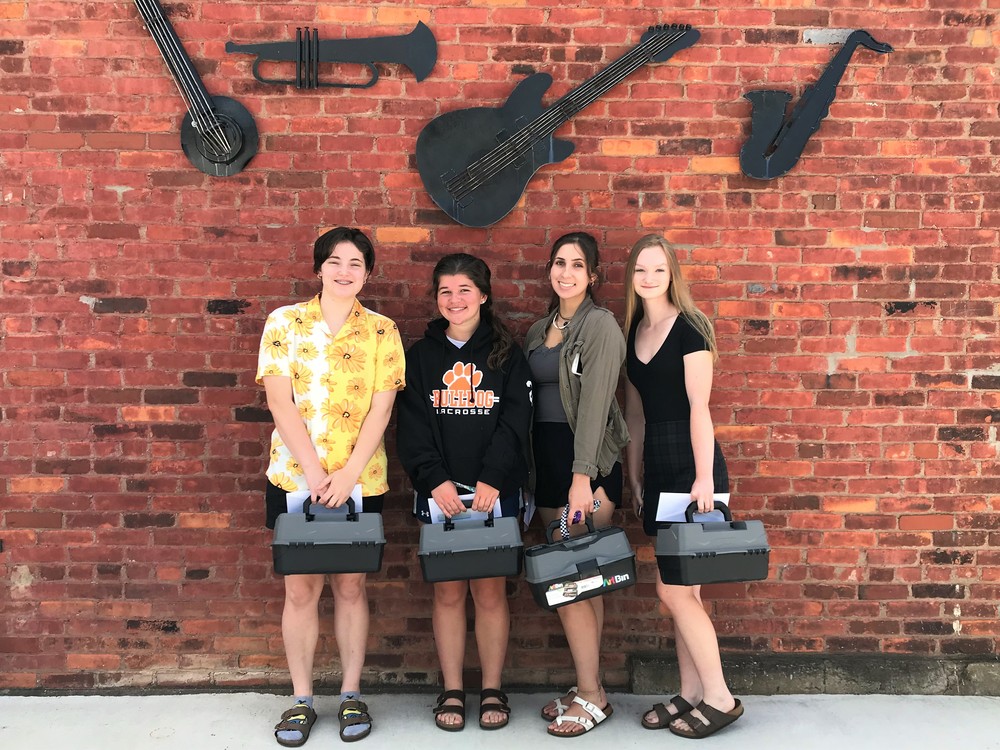 4 students holding art boxes