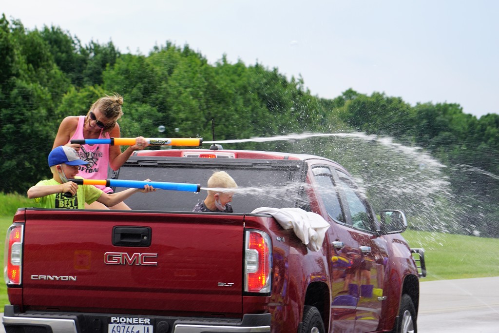 mom and kids in back of truck with super soakers
