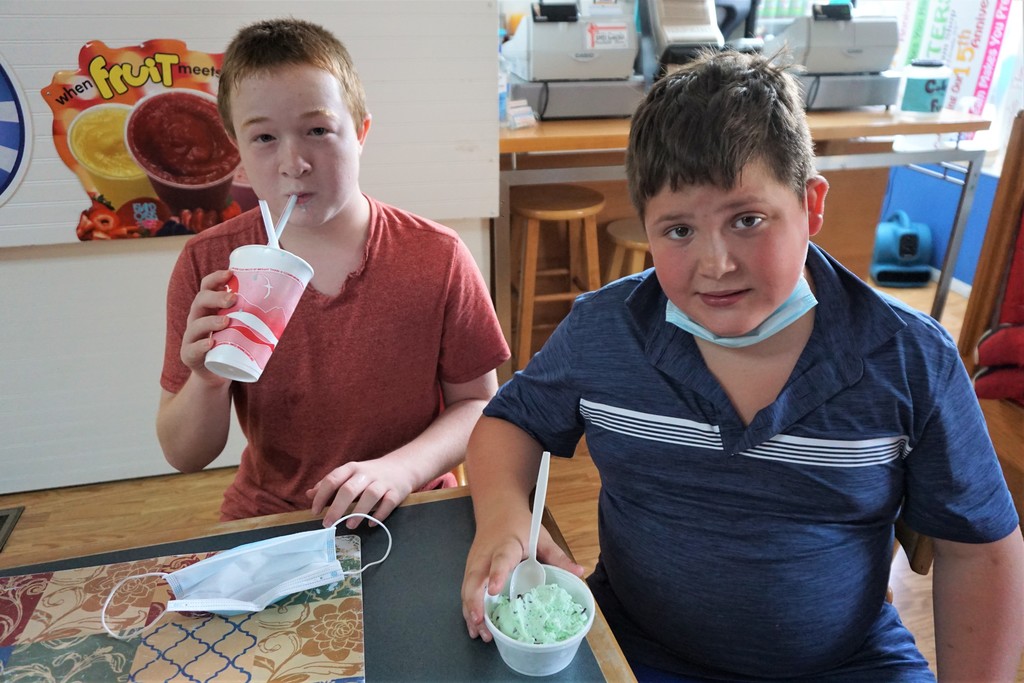 two students one enjoying mint ice cream and one enjoying a slushie