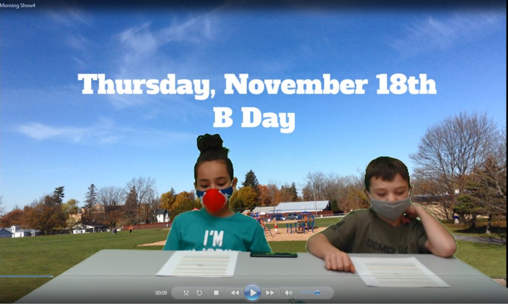 two students at desk with playground on green screen