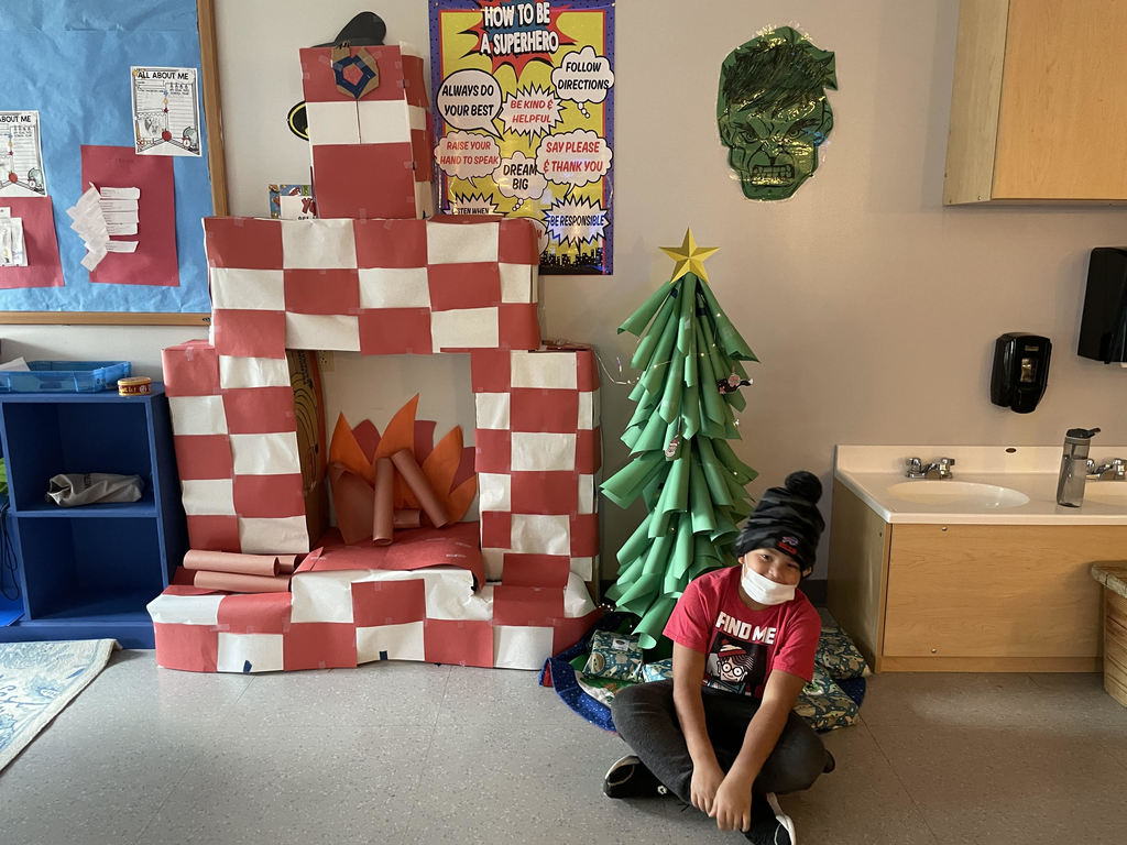 student next to fake fireplace and tree