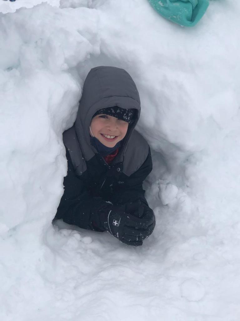 student peeking out from snow fort
