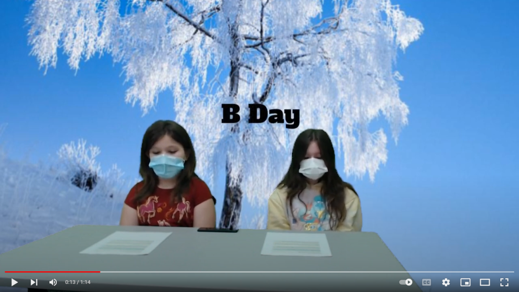 two students at news table with icy trees on the green screen