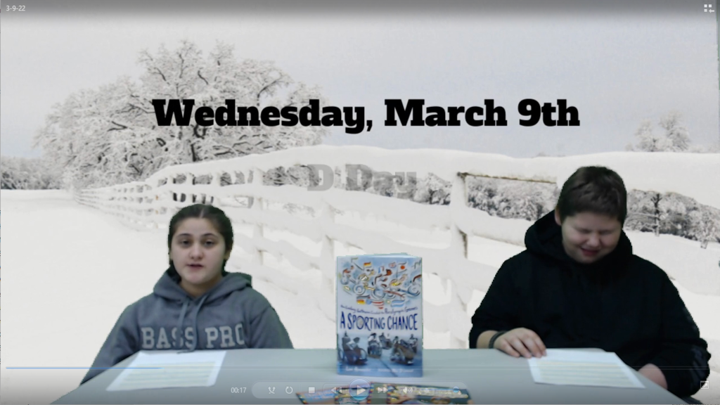 Two students at news desk with a book between them and a snowy fence and field on green screen