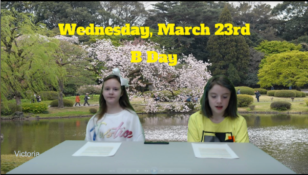 two students at news desk with a pond and  park in bloom on green screen