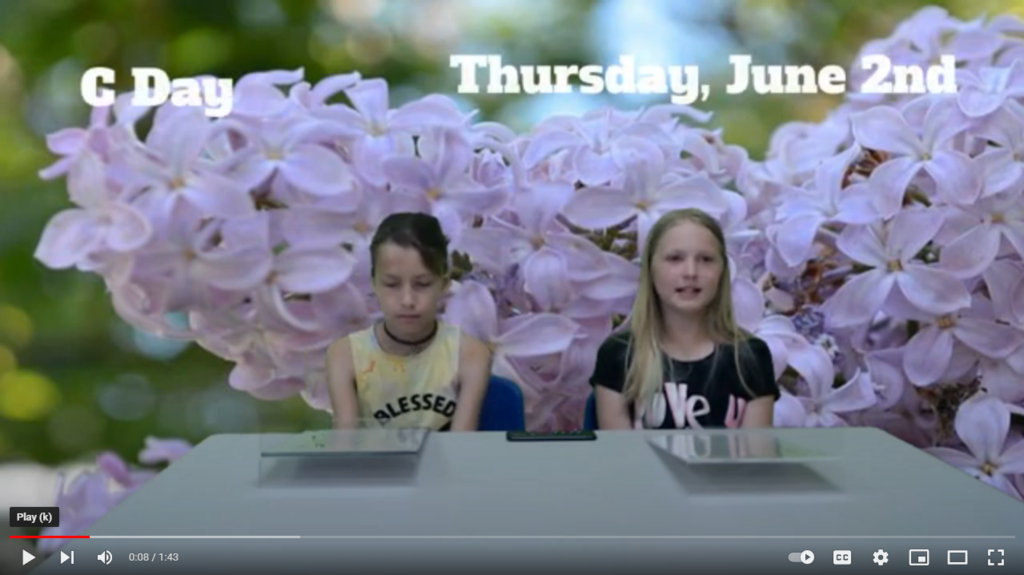 two students at news desk with lilacs on green screen