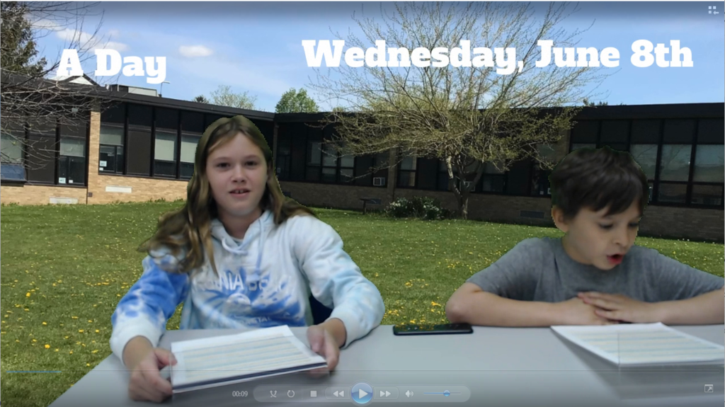 two students at news desk with elementary school on green screen
