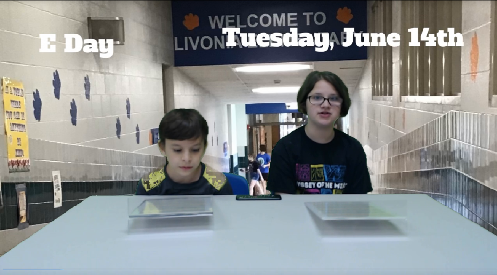 two students at news desk with school hallway on green screen behind them