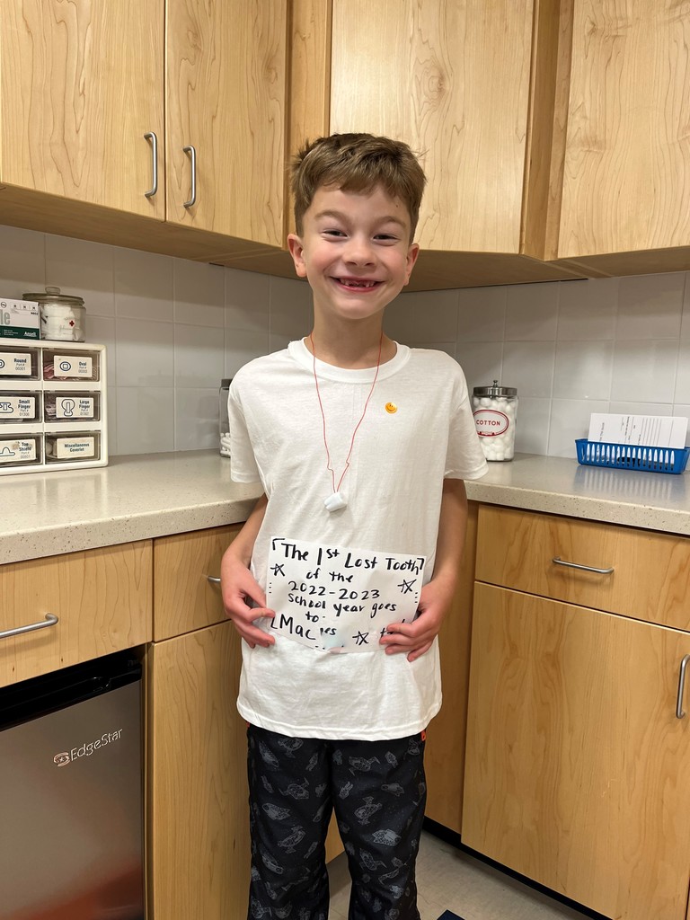 student smiling holding paper sign that says first lost tooth this school year