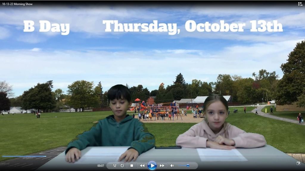 two students at news desk with ES playground in background
