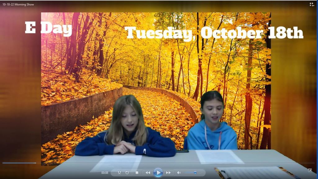 two students at news desk  with fall backdrop