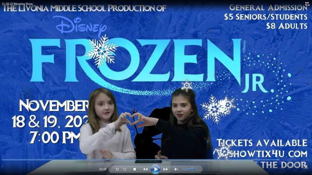 two students making a heart with their hands with frozen on greens screen and falling snowflakes