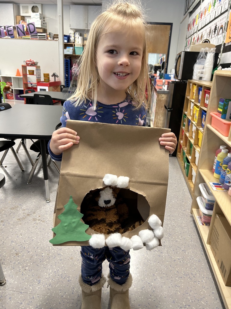 students holding paper bag made to look like a cave for a stuffed animal