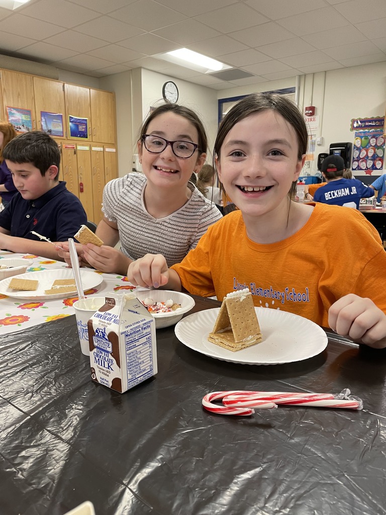two smiling students with graham cracker house