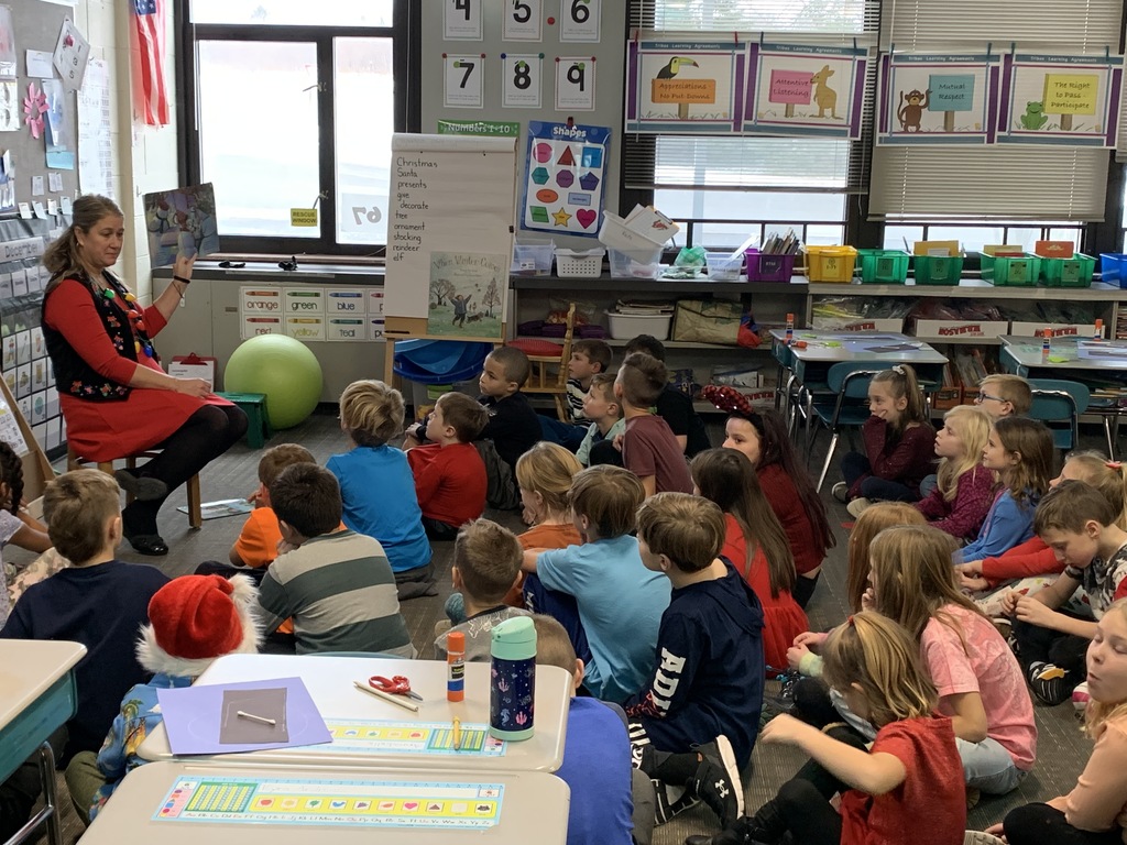 teacher reading to students sitting on floor around her