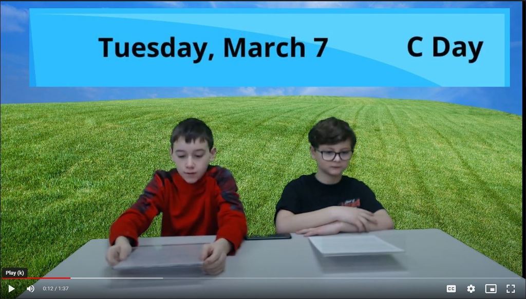 two students at news desk with grass on green screen