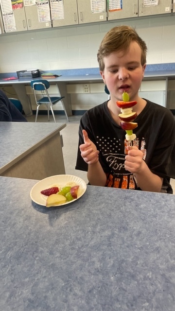 student with fruit kababs